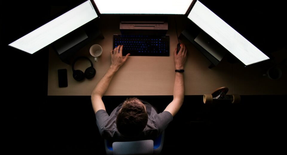 man facing three computer monitors while sitting